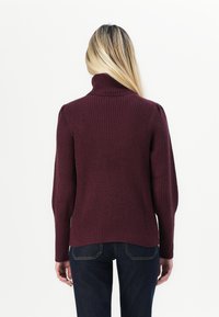 Burgundyribbade polotröja med långa ärmar, som har en figurnära passform och mjuk textur. Sömmar vid axlarna.