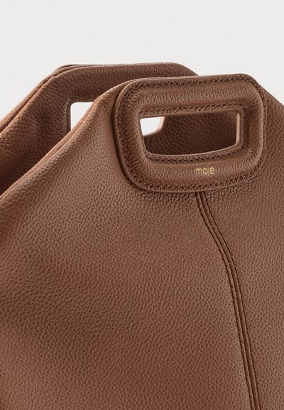 Καφέ δερμάτινη τσάντα με υφή, ορθογώνιες λαβές με κοψίματα και διακριτικό χρυσό λογότυπο "maje" κοντά στην άκρη της λαβής.