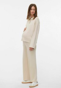 Beige zwangerschapsoutfit bestaande uit een polo met lange mouwen en wijde broekspijpen, gemaakt van zachte stof, met een relaxte pasvorm en subtiele textuur.
