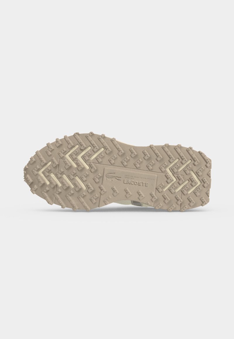 Beige Gummisohle mit tiefem Profil und dem in der Mitte eingeprägten Lacoste-Logo.