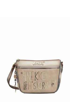 Beige Umhängetasche mit geprägtem Text "Anekke Makes History", dekorativem Anhänger und strukturiertem Leder. Verfügt über einen verstellbaren Riemen und kontrastreiche Akzente.