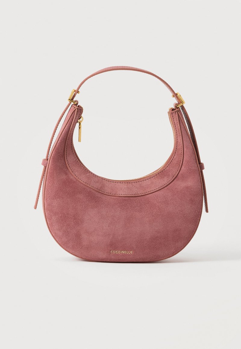 Sac à main en daim rose poudré en forme de croissant avec fermeture éclair dorée et bandoulière courte, avec petit logo doré "Coccinelle" en bas au centre.