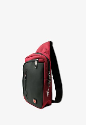 Sac à bandoulière rouge et noir avec plusieurs compartiments zippés et une sangle noire ajustable, se tenant debout sur un fond blanc.