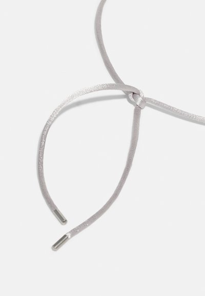 Heledad hallhalli nöör, millel on sile tekstuur, keskel sõlm ja igas otsas metallotsikud.