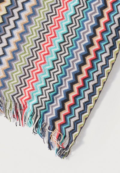 Tissu à motifs zigzag colorés avec des bords frangés dans des nuances de bleu, rouge, vert, noir et beige sur un fond blanc.