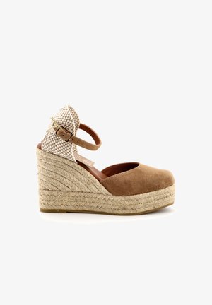 Bruine suède wedge-schoen met een geweven stoffen hak, verstelbare enkelband en een gevlochten jute detail langs de zool. Glad afgewerkt.