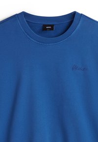 Sweat-shirt bleu à col rond avec col côtelé, petit logo Vans brodé sur la poitrine et étiquette de marque intérieure au niveau de l'encolure.