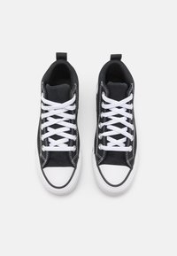 Svarta kanvas sneakers med vita snören och gummikappor för tårna. Har vit sömnad och texturerade vita gummisulor. Ovanifrån.