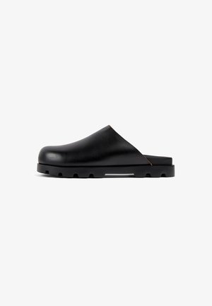 Sabots en cuir noir avec une finition lisse, un bout arrondi et une semelle en caoutchouc noir robuste présentant des accents texturés et un design bas.
