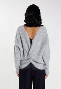Szary, oversize'owy sweter dziany z dekoltem w serek i skręconym tyłem; miękka, puszysta tekstura; długie rękawy i luźny krój.