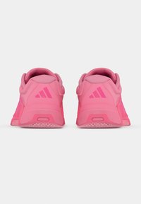 Ζευγάρι φωτεινά ροζ αθλητικά παπούτσια που φαίνονται από πίσω, με επενδεδυμένους γιακάδες και υφασμένο πέλμα σε απλό λευκό φόντο.