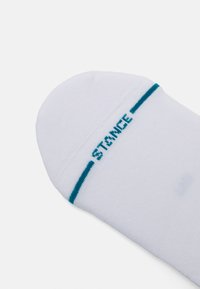 White sock with blue accents, featuring a rounded toe and "STANCE" logo stitched in blue. Material appears soft and textured.