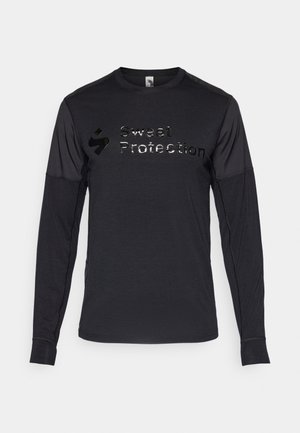 Czarna sportowa koszulka z długim rękawem o teksturowanej tkaninie, z błyszczącym logo "Sweet Protection" na klatce piersiowej. Miękki i dopasowany krój.