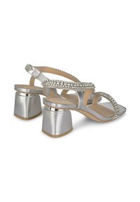 Sandalias de tacón plateadas con un tacón bloque y tiras entrelazadas adornadas con piedras de strass en la parte superior y el soporte del talón.