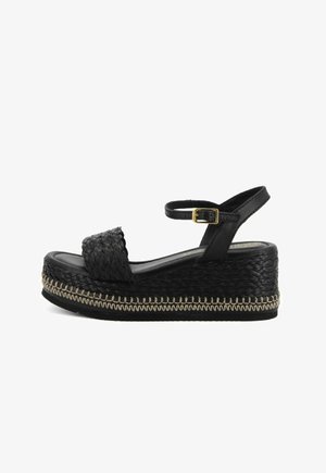 Sandalia cuña negra con una banda tejida en el pie, una correa en el tobillo con hebilla dorada y detalles de yute cosido a lo largo de la suela.