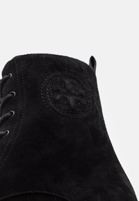 Bottes de cheville en daim noir avec un logo texturé, bout rond et design à lacets avec coutures renforcées. Fini lisse avec une texture douce.