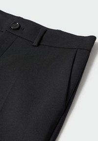 Zwarte op maat gemaakte broek met een platte voorkant, enkele knoopsluiting en gladde, lichte stof. Gedetailleerd met scherpe plooien en zakken.