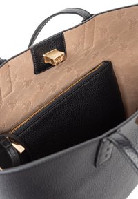 Czarna skórzana torebka o strukturalnym wykończeniu, z beżowym wnętrzem i złotym zapięciem. W zestawie znajduje się wewnętrzna kieszeń na zamek.