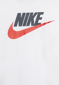 White cotton t-shirt featuring the Nike logo in dark gray and red, with a smooth texture and sleek design.