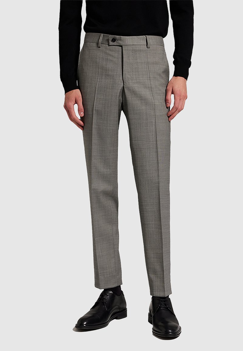 Man wearing slim-fit gray dress pants with crease, black long-sleeve top, black socks, and black leather dress shoes.