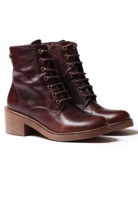 Botas de tobillo de cuero marrón con puntera redonda, cordones en la parte delantera y acabado texturizado. Tacón cuadrado y suela de goma para mayor tracción.