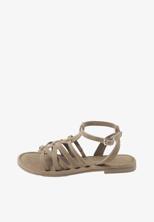 Beiger Gladiator-flacher Sandale mit mehreren Riemen und einem Knöchelriemen mit einer kleinen Metallschnalle vor weißem Hintergrund.