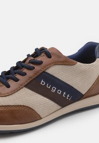 Sneaker casual in rete beige, con dettagli in pelle marrone, lacci blu navy e branding "bugatti" sulla striscia laterale blu navy e marrone.