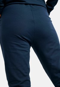 Legíny z námorníckej modrej elastickej látky s hladkou textúrou, s priliehavým strihom bez viditeľných kovových prvkov alebo vzorov.