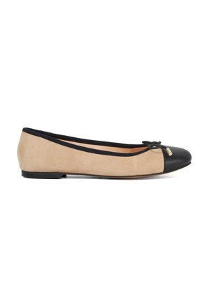 Ballerines en daim beige avec un bout en cuir noir. Dotées d'un petit nœud et d'un accent doré sur le côté. Design à profil bas.