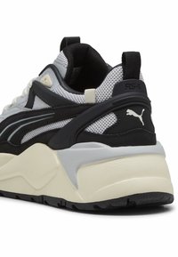 Tenisky RS-X mají šedou síťovinu na svršku, černé semišové detaily a silnou krémovou podrážku s textured černou gumovou výstuží.