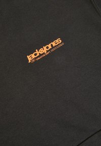 Felpa nera con logo arancione "jack&jones" e testo "CREATIVE DEPT.", realizzata in tessuto liscio e morbido, design piatto e senza motivi visibili.