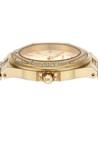 Zelta tonis pulksteņi ar kristāla akcentiem uz rāmīša un siksniņas, apaļa sejas forma, gaiša zelta ciparnīca, arābu stundu marķieri un MK logo uz kronīša.