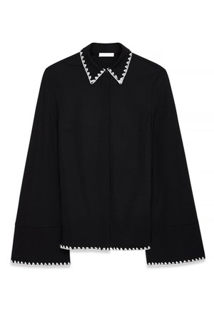 Mustmustärk musta pluus terava kraega, millel on valge sakiline äär, pikad varrukad ja sirge lõige. Sile tekstuur ja lihtne disain.