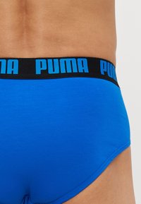 Modré bavlnené slipy s čiernym pásom, na ktorom je modrým písmom logo "PUMA". Hladký povrch a priliehavý dizajn pre pohodlie.