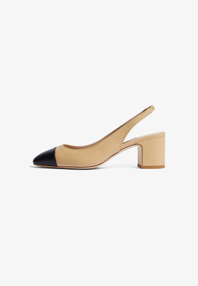 Chaussure slingback en cuir beige avec un bout pointu noir. Elle possède un talon épais et une texture lisse, avec des détails de couture minimalistes.