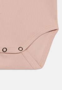 Rosa ribbede babybodyhjørne med metallknapper, med en myk tekstur og avrundede kanter for enkel påkledning.