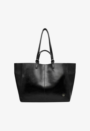 Černá kožená taška přes rameno s dvojitými rukojeťmi, hladkým povrchem a malým kovovým logem ve spodní pravé části.