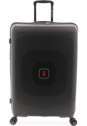 Valise rigide noire avec des rayures diagonales, logo rouge central, poignée télescopique et quatre roues pivotantes.