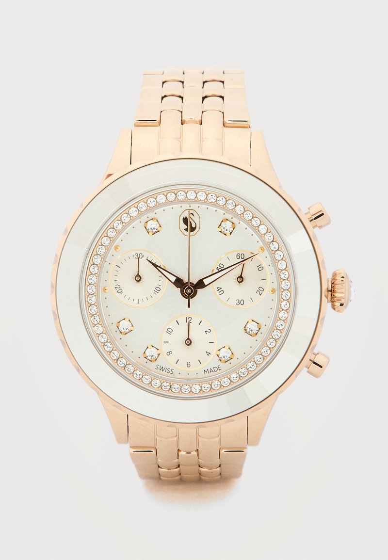 Ρολόι χειρός από ροζ χρυσό με δείκτες από διαμάντια, τρεις υποενδείξεις, στεφάνη διακοσμημένη με κρύσταλλα και μπρασελέ από συνδεδεμένα μεταλλικά στοιχεία.