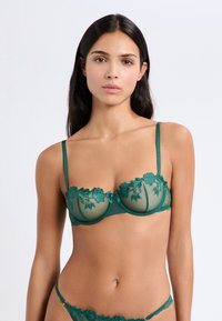 Groene kanten beha met bloemenborduursels, onderwire ondersteuning, doorzichtige meshpanelen en verstelbare bandjes, aangevuld met bijpassende slip.