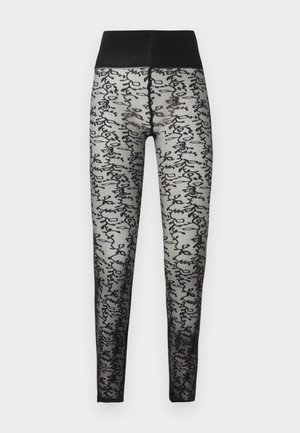 Mustad läbipaistvad retuusid kõrge, ühtlase vöökohaga ja jalgadel helehallil taustal musta abstraktse kirjakujundusega.