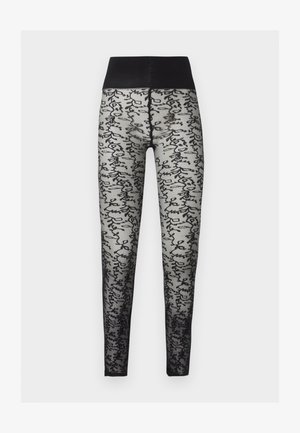 Mustad läbipaistvad retuusid kõrge, ühtlase vöökohaga ja jalgadel helehallil taustal musta abstraktse kirjakujundusega.