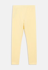 Kollased pehmetest kangast põlvikud, millel on elastne vöökoht. Omadused hõlmavad kitsast lõiget ja täispikkust, sobivad lõdvestunud kandmiseks.