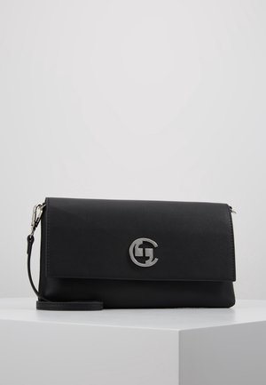 Sort læderclutch med sølv cirkulært logo og aftagelig håndledsrem, placeret på en hvid overflade mod en ensartet lys baggrund.