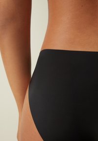 Schwarzer hochgeschnittener Bikiniunterteil aus glattem, elastischem Material mit nahtlosem Design und minimalistischer Schnittführung, der eine elegante, einfarbige Optik präsentiert.