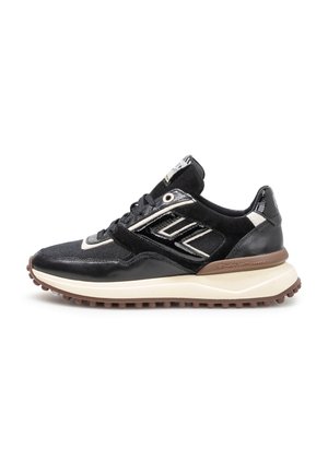Zapatilla negra y blanca con suela marrón, diseño con cordones, materiales mixtos y un patrón texturizado en la suela.