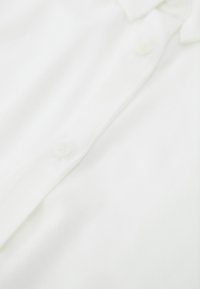 Weißes Hemd mit Knopfleiste, ausgestattet mit einer glatten Textur, weichem Material und klassischem Kragen. Mit drei Knöpfen an der Knopfleiste.