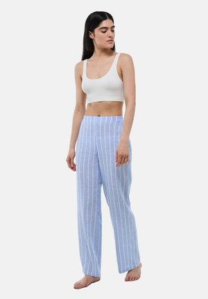 Crop top blanc à côtes associé à un pantalon de pyjama bleu clair avec des rayures blanches verticales. Les deux sont de coupe décontractée et en tissu doux.