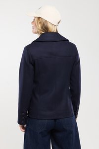 Veste en mélange de laine navy avec un col structuré, des poignets boutonnés et une silhouette cintrée, vue de dos. Associée à un pantalon en denim foncé.