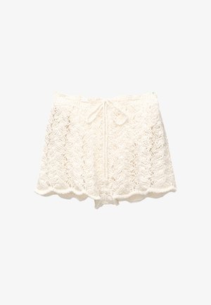 Weiße Häkelshorts mit gewelltem Saum, die ein strukturiertes, offenes Strickdesign aufweisen und über einen Kordelzugbund für eine verstellbare Passform verfügen.